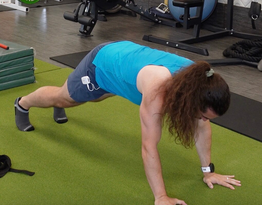 Dr. John beginning in a god plank position supported by his hands under his shoulders and standing on his toes for javelin mobility